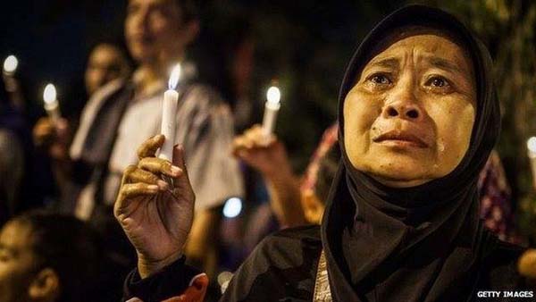 Một người phụ nữ bật khóc khi cầu nguyện cho các hành khách trên chuyến bay QZ8501.