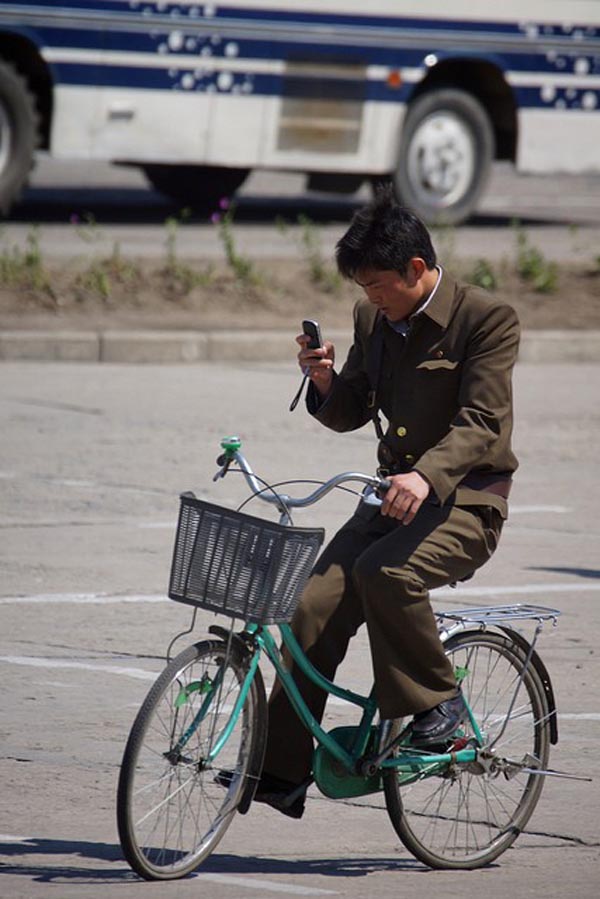 Một người đàn ông đang sử dụng điện thoại khi ông đang đạp xe ở Hamhung.