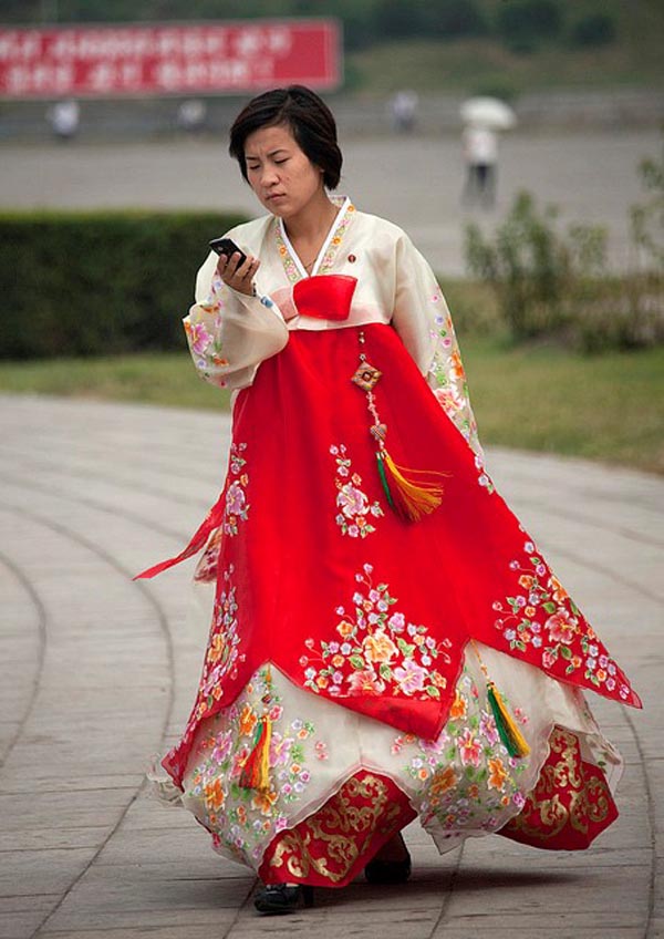 Một thiếu nữ Triều Tiên mặc trang phục truyền thống chăm chú nhìn vào màn hình điện thoại khi cô đang tản bộ trong công viên ở Bình Nhưỡng.