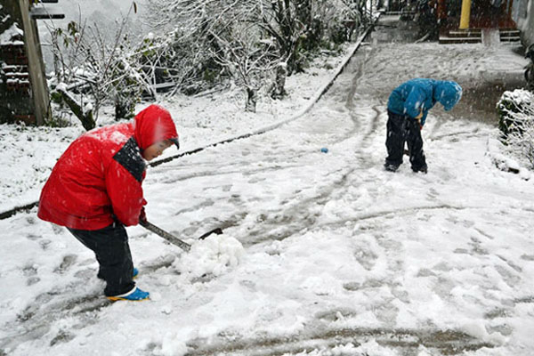 Hai em nhỏ đang cào tuyết để đường đỡ trơn.