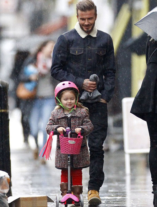 Ông bố điển trai mỉm cười hạnh phúc khi thấy cô nhóc Harper thích thú đi xe scooter trên đường phố lất phất mưa bay.