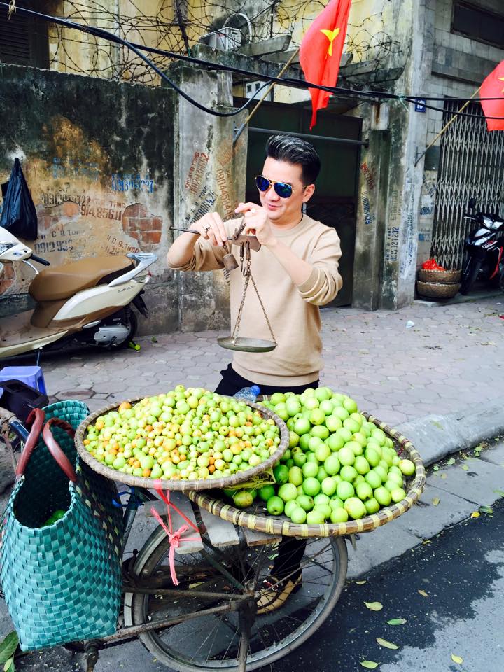 Đàm Vình Hưng hào hứng tập cân táo tại một xe hàng rong trên phố cổ Hà Nội.