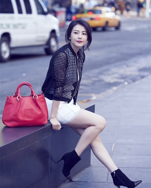 Cá tính khi phối jacket lưới tông đen, miniskirt trắng và bốt cổ ngắn cao gót đồng điệu. Cô dùng túi tông đỏ sang trọng làm điểm nhấn.
