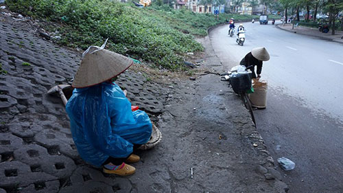 Dù trời không mưa, người phụ nữ làm nghề lao động tự do đợi khách hàng dưới gầm cầu Long Biên vẫn mặc áo mưa để chống rét.