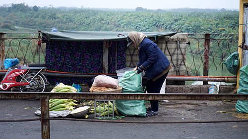 Người phụ nữ bán ngô trên cầu Long Biên với chiếc lều chắp vá chống gió rét.