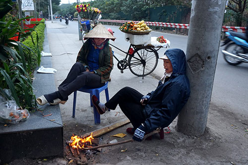 Hai phụ nữ bán hoa quả dạo đốt lửa sưởi trên đường Xuân Diệu.