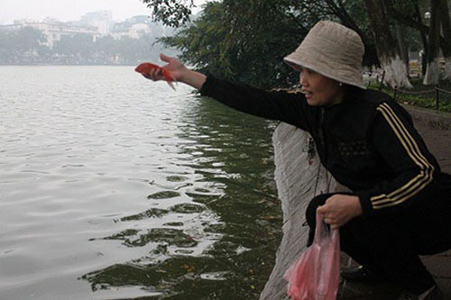 Một người dân hào hứng phóng sinh cá chép ở khu vực Hồ Gươm.