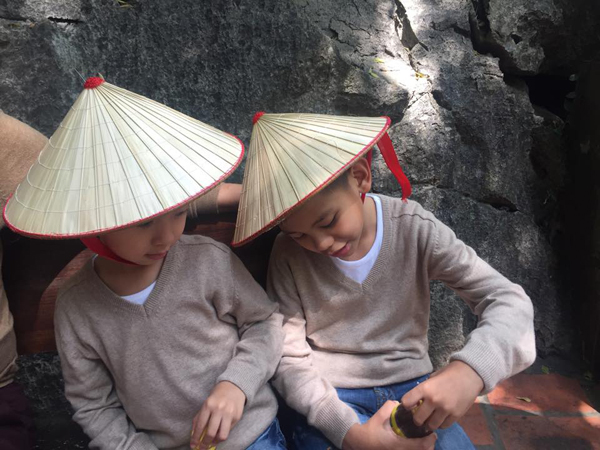 Hai nhóc tỳ thích thú đội nón lá để tránh nắng.