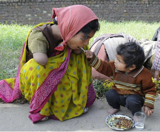 Em bé hai tuổi đút thức ăn cho người mẹ tật nguyền.