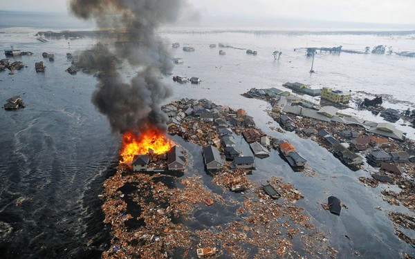 Các căn nhà bốc cháy ngùn ngụt bị cuốn trôi ra biển bởi những cột sóng thần ở Sendai, quận Miyagi.