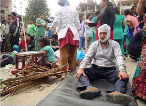 Nhân viên y tế điều trị cho những người bị thương trong thảm kịch tại thủ đô của Nepal trong khi nhiều người khác nằm dưới sàn đất chờ nhân viên y tế.