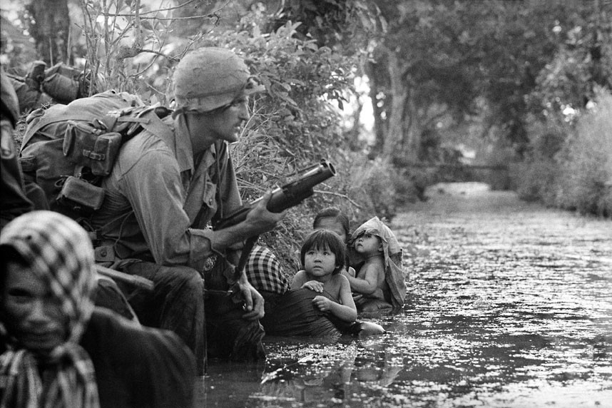 Ánh mắt sợ hãi của những em nhỏ Việt Nam khi ngước nhìn một lính dù Mỹ cầm súng phóng lựu M79 tại khu vực Bàu Trai, cách Sài Gòn 32 km. Ảnh: AP