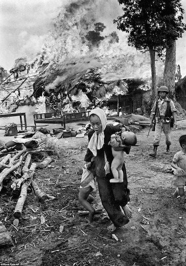 Người phụ nữ vội vã kéo hai em nhỏ khỏi đám cháy đang bùng lên tại nhà của họ ở gần Tây Ninh, năm 1963. Ảnh: AP