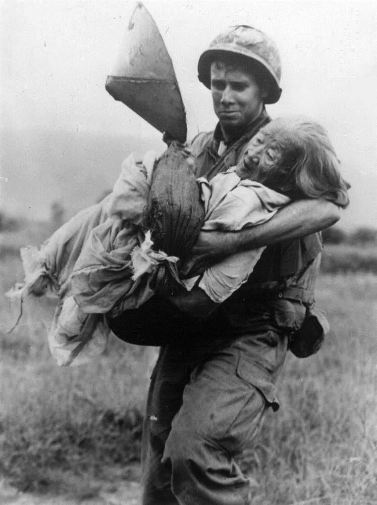 Sĩ quan thủy quân lục chiến Mỹ bế một phụ nữ Việt Nam lên trực thăng cứu hộ.