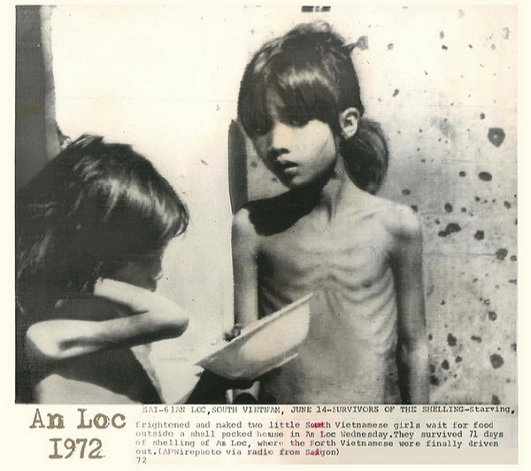 Hai bé gái gầy trơ xương chờ được phát thực phẩm bên ngoài một ngôi nhà hư hại bởi pháo kích tại An Lộc, Bình Phước, ngày 14/6/1972. Ảnh: AP
