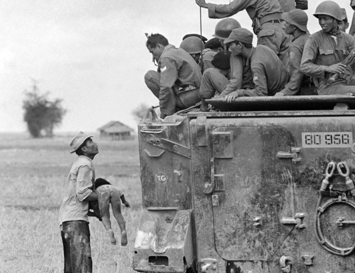 Người cha ôm xác con khi nhóm lính Việt Nam Cộng hòa nhìn xuống từ xe thiết giáp ngày 19/3/1964. Tác phẩm của Horst Faas, phóng viên AP, giành giải báo chí danh giá Putilizer năm 1965.