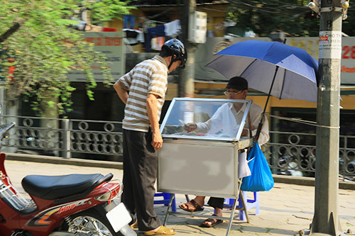 Một người bán vé số dùng ô chống nắng trên phố Kim Mã (Ba Đình).