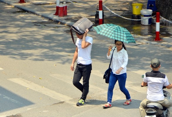 Hai sinh viên Đại học công đoàn trên đường Tây Sơn phải dùng ô, cặp sách để che nắng trên đường đến trường.