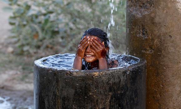 Một bé gái tắm trông bồn nước để chống chọi lại cái nắng gay gắt.