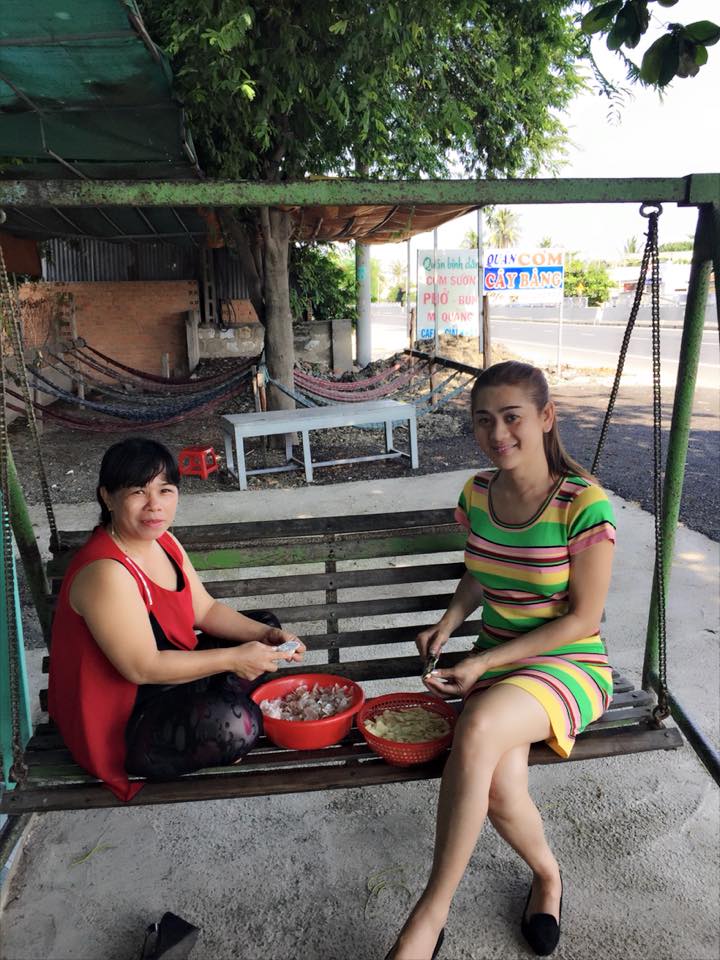 Lâm Chi Khanh ngồi bóc tỏi cùng một người bạn, nữ ca sĩ chuyển giới ngày càng nữ tính và dịu dàng.