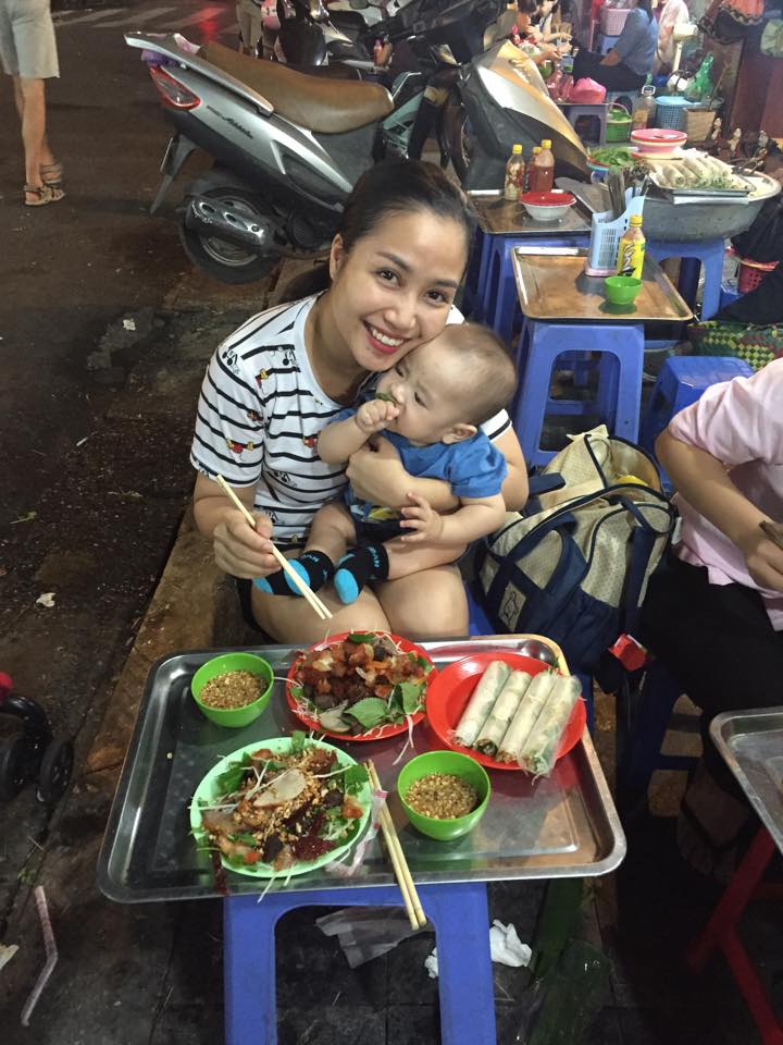 Nữ MC xinh đẹp ăn mặc rất giản dị bế con trai út ngồi ăn nộm ở vỉa hè Hà Nội.