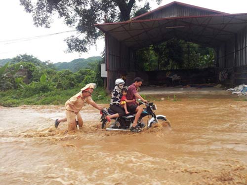 Hình ảnh 2 CSGT tại huyện Mai Sơn (tỉnh Sơn La) không nề hà dòng nước chảy xiết để đẩy xe giúp người dân vượt qua đoạn đường nguy hiểm.