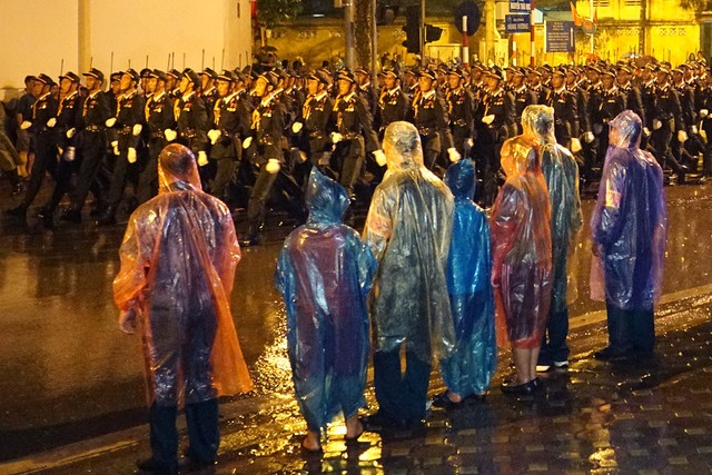 Người dân đội mưa giữ nguyên vị trí theo dõi đoàn diễu hành.