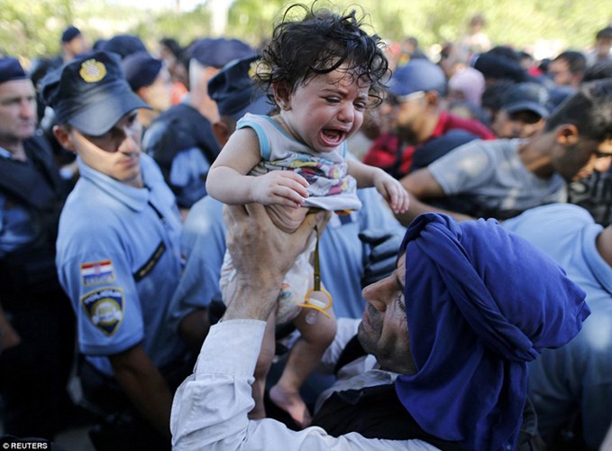 Một em bé khóc thét khi bị dòng người tị nạn xô đẩy để lên chuyến tàu sang Áo.