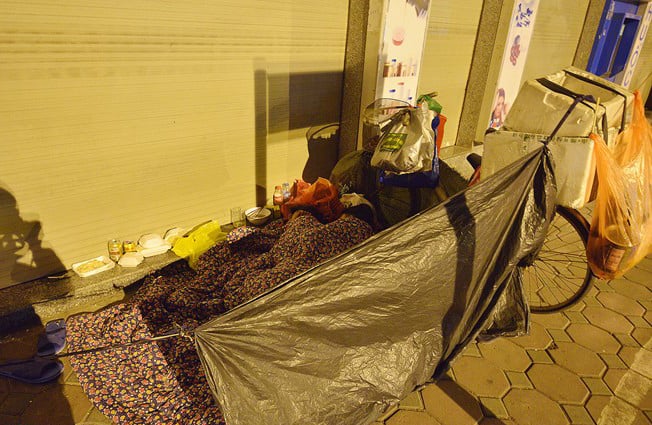 Dùng mảnh áo mưa mắc lều ngủ trên phố. Hình ảnh được ghi lại trên phố Nguyễn Thái Học.