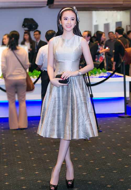 Angela Phương Trinh cũng là nhân vật thu hút ống kính trong chương trình. Cô chọn đầm xòe màu xám của nhà thiết kế Lê Thanh Hòa, cài nơ điệu đà trên tóc.