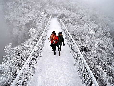 19. Thiên Môn Sơn, Trung Quốc: Cảnh vật phủ kín trong tuyết trắng tạo ra một bức tranh đơn sắc tuyệt đẹp mà điểm nhấn là hai cô gái đang rảo bước trên cây cầu ở độ cao 1400 mét so với mực nước biển. Ảnh: Reuters.