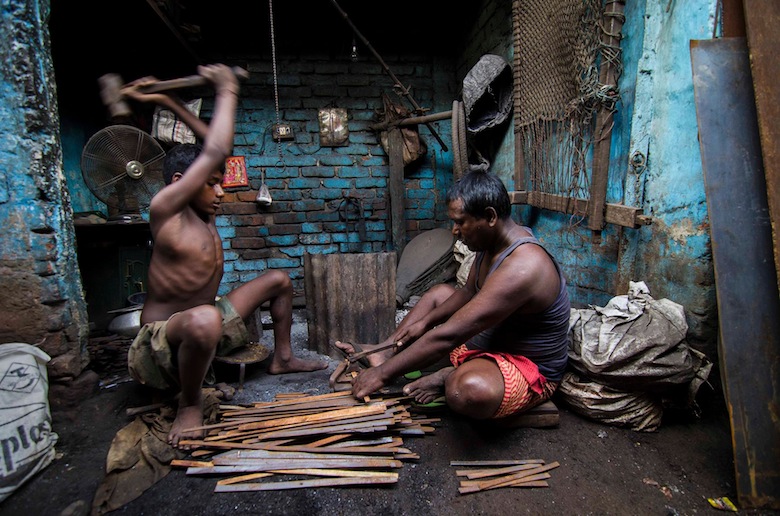 Bức ảnh một người đàn ông trẻ tuổi và cha của anh ta đang làm việc trong xưởng kim loại của họ. (Ảnh Subhasis Sen)
