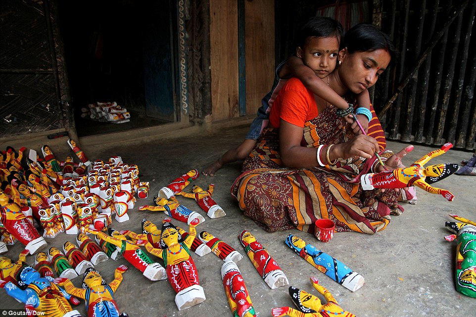 Bức ảnh mô tả công việc thủ công của một người phụ nữ Ấn Độ. Người phụ nữ vừa trông con vừa làm những con búp bê bằng gỗ (Ảnh Goutam Daw).