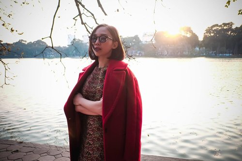 Tóc Tiên diện đầm suông kết hợp với áo choàng đỏ ngắm hoàng hôn đang dần buông trên bờ hồ ở Hà Nội.