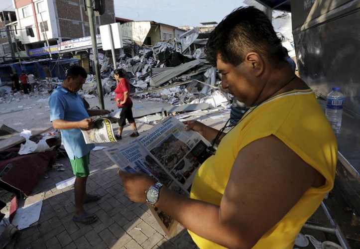 Mọi người đọc thông tin về trận động đất trên báo chí.