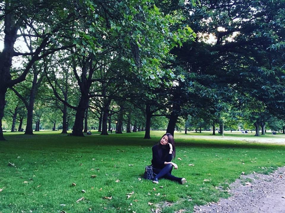 Hoàng Thùy Linh ngồi trầm tư trên thảm đỏ xanh mướt tại một công viên ở London, Anh Quốc.