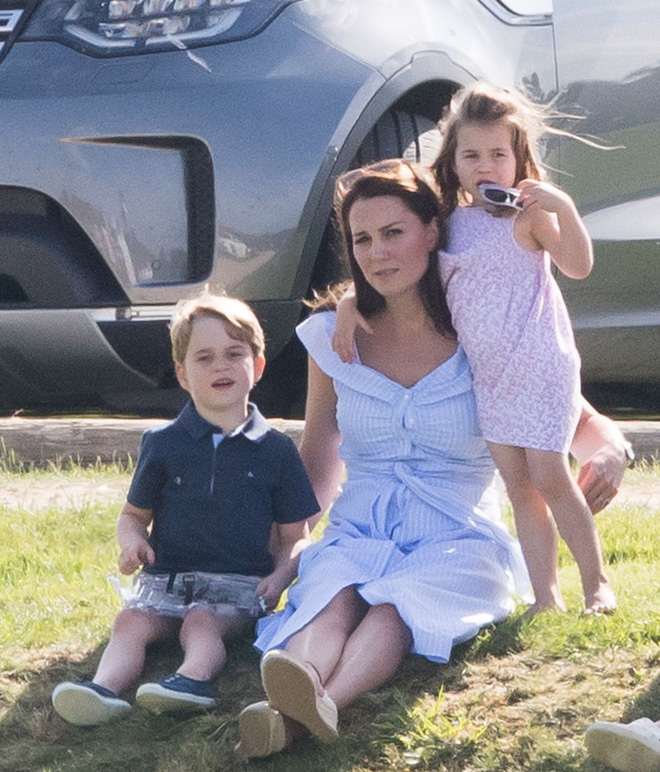 Công nương Kate cùng với hoàng tử George, công chúa Charlotte ngồi trên bãi cỏ cổ vũ hoàng tử William đang thi đấu bên dưới.