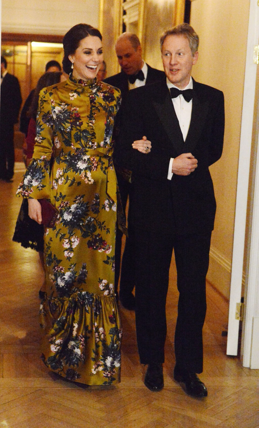 Kate Middleton diện thiết kế của thương hiệu Erdem, giày và túi xách của nhà mốt Jimmy Choco. Chiếc đầm họa tiết hoa dài phần nào che đi phần bụng của công nương Anh, giúp tôn lên được vẻ quý phái cho cô cùng với kiểu tóc bới cao. 
