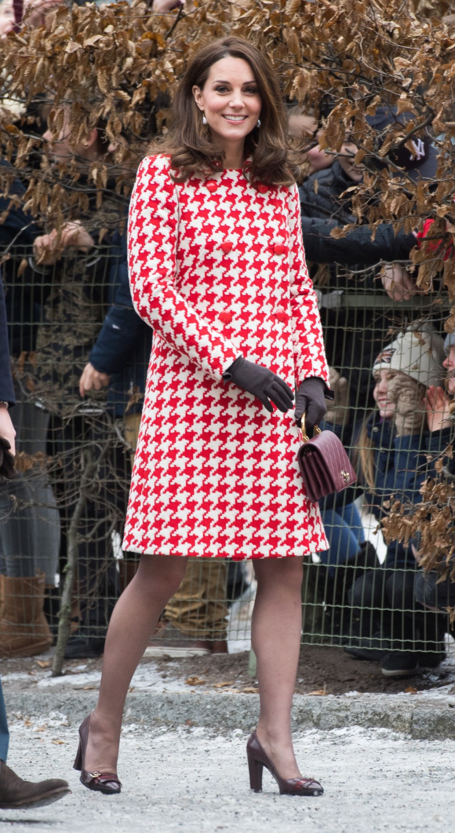 Tại một sự kiện khác, cùng diện phong cách tương tự nhưng lần này Kate Middleton nổi bật hơn với mẫu váy len có họa tiết đỏ trắng cũng của nhà mốt Alexander McQueen và sử dụng lại túi xách màu đỏ mận của Chanel, kết hợp cùng bộ với giày cao gót.