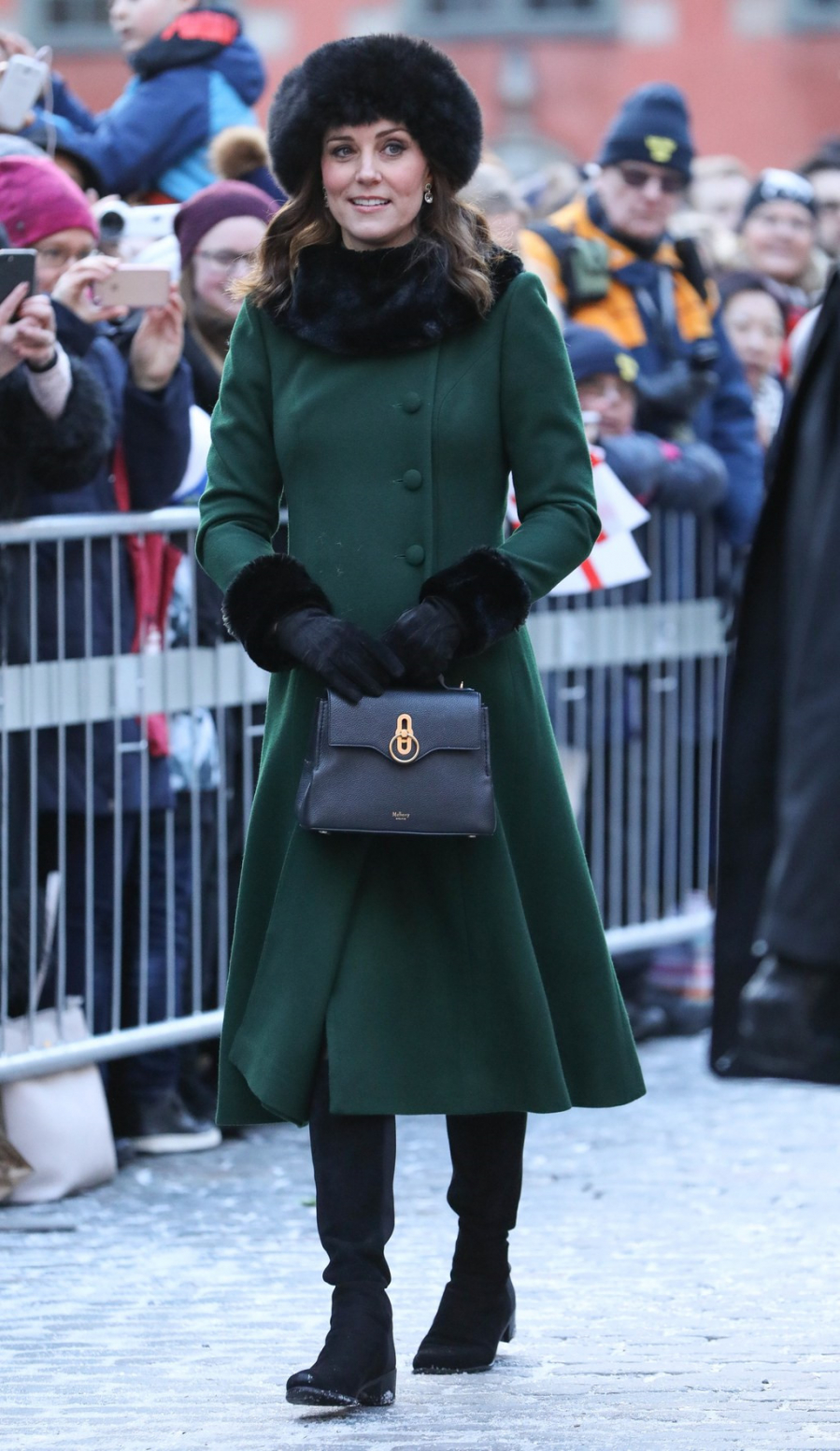 Công nương Kate diện đầm dáng măng tô màu xanh rêu của thương hiệu Mulberry được kết hợp ăn ý với màu xanh sẫm của túi xách Stuart Weitzman . Từ mũ lông cáo, găng tay đến đôi boots của công nương Kate cũng đều đến từ thương hiệu đắt tiền. 