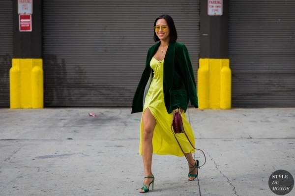 Blogger thời trang Aimee Song sải bước trên đường phố trong bộ váy lụa màu vàng chanh và chiếc áo khoác nhung màu xanh đậm.    