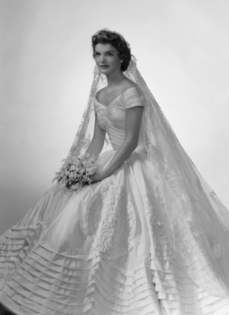 Trong hôn lễ cùng Tổng thống John F. Kennedy năm 1953, thiết kế đầm lụa màu ngà với phần eo ôm gọn thân hình mảnh mai và những tầng hoa văn in nổi mang đến vẻ thanh lịch cho nàng dâu mới.   