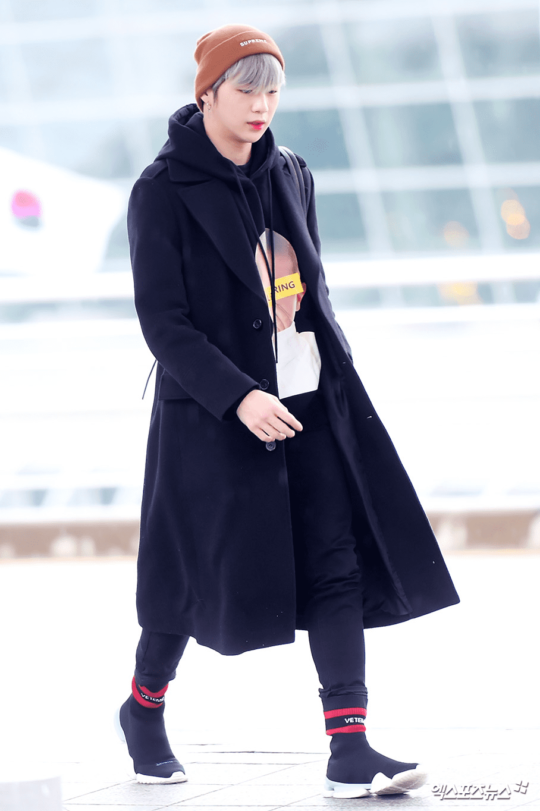 Kang Daniel đã lấy ý tưởng thời trang từ trò chơi Assassin’s Creed để chọn cho mình set đồ sân bay như ý. Áo khoác da lộn màu đen cùng áo phông cá tính và mũ len màu cam đào giúp anh chàng chống lại thời tiết lạnh lẽo của mùa đông Hàn Quốc.    