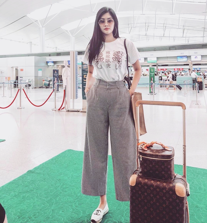 Huỳnh Tiên ghi điểm với thời trang sân bay đơn giản, tiện dụng. Vẫn là áo phông yêu thích song mỹ nhân 9X lại mix ăn ý với quần lửng ống rộng kẻ và giày xỏ Chanel.    