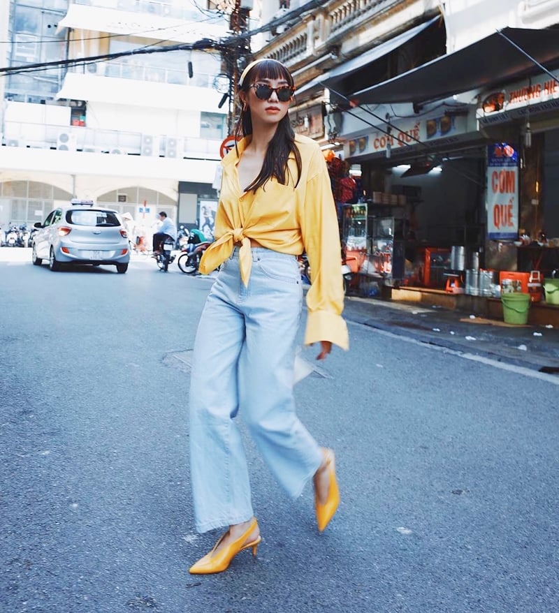 Salim biến tấu bộ cánh street style bằng cách buột vạt và mở rộng cúc cổ của thiết kế sơ mi vàng rực. Cô nàng tạo sự đồng điệu cho trang phục với lựa chọn băng đô và giày đế thấp mang màu vàng ton-sur-ton, phối cùng quần denim ống rộng mang nét bụi phủi.    