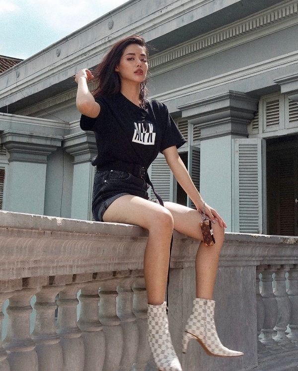 Khánh Linh The Face ghi điểm tuyệt đối với áo phông đen in slogan, phối cùng quần jean và boots cao gót đắt đỏ của Louis Vuitton.    