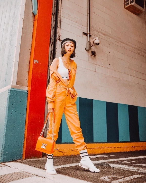 Cô nàng chọn bộ jumpsuit màu cam mang phong cách công nhân, fashionista đến từ Philippines còn tăng thêm vẻ sành điệu cho mình bằng cách sử dụng loạt phụ kiện đi kèm như mũ nồi, giày sneaker Vetements và túi xách của Louis Vuiiton.    