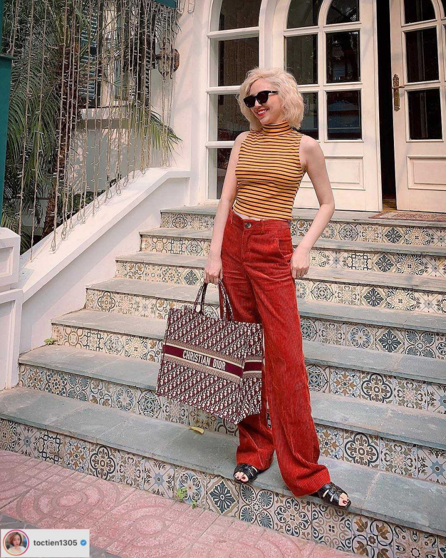 Tuần này, ca sĩ Tóc Tiên biến hoá với phong cách retro cùng quần ống rộng và áo crop top cao cổ, thêm phụ kiện túi Christian Dior. Cách lựa chọn màu sắc đối lập đỏ-vàng tạo vẻ ngoài nổi bật.    