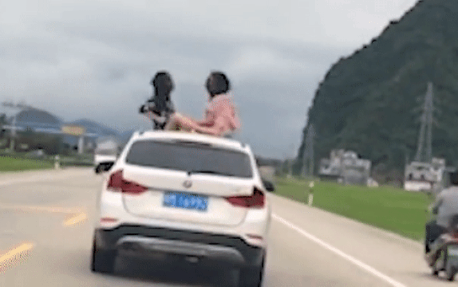Hai bé gái ngồi chơi trên nóc ô tô khi xe đang chạy tốc độ cao, phản ứng của người mẹ mới đáng trách