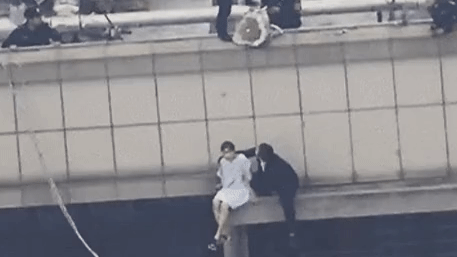 Cô gái ôm bó hoa hồng ngồi vắt vẻo trên sân thượng tầng 30 định nhảy lầu tự tử